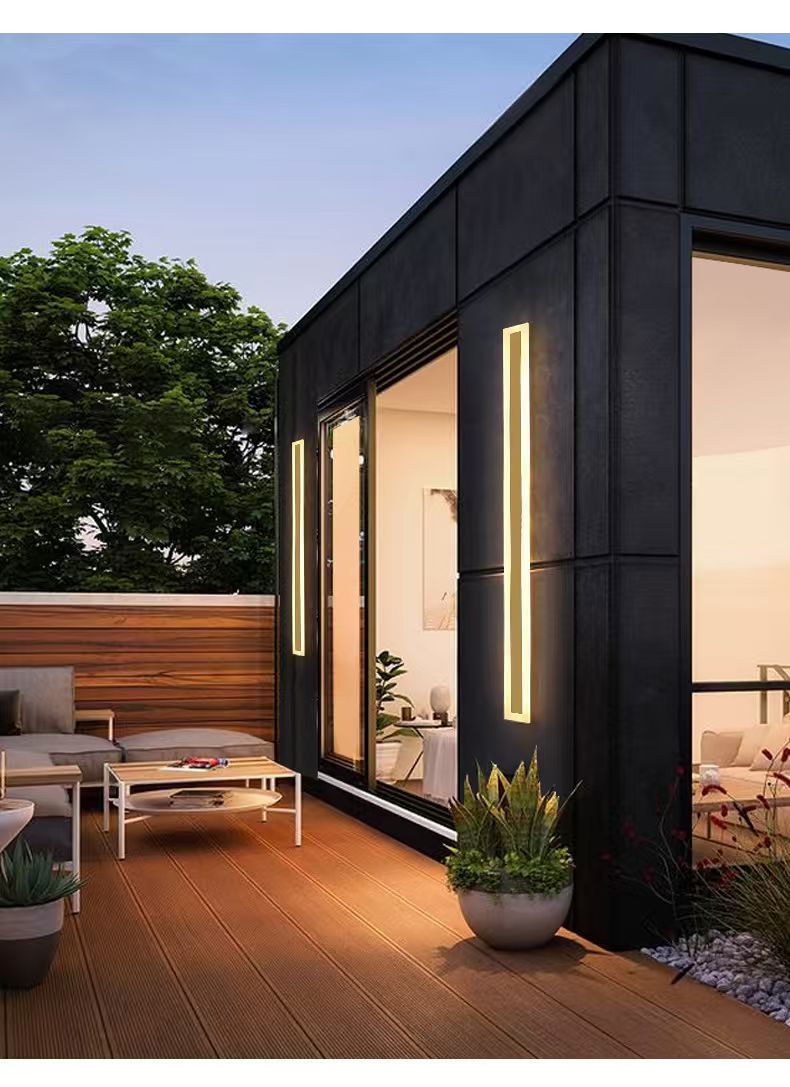 Pair of gold linear outdoor wall lights on a modern courtyard exterior