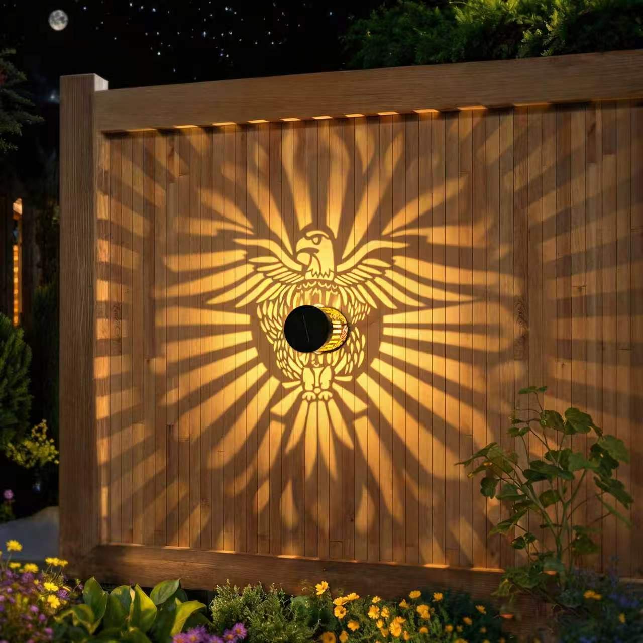 AML2166 Eagle solar courtyard light projecting a decorative shadow pattern on a wooden fence