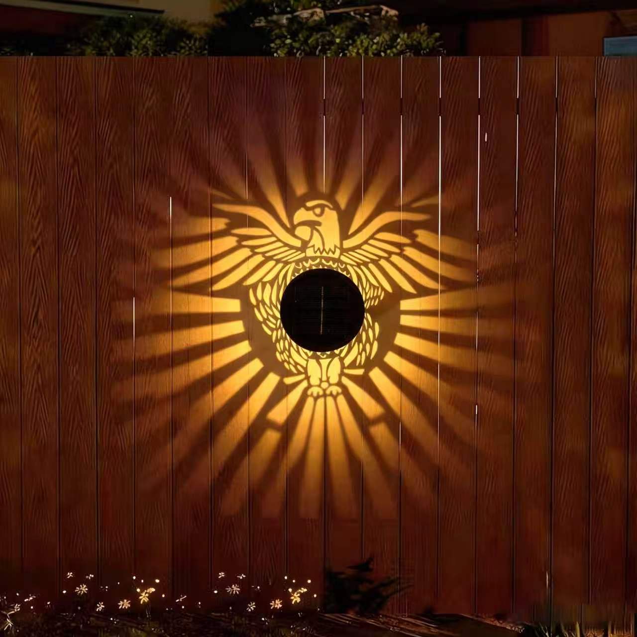 Eagle pattern solar courtyard light on a wooden fence