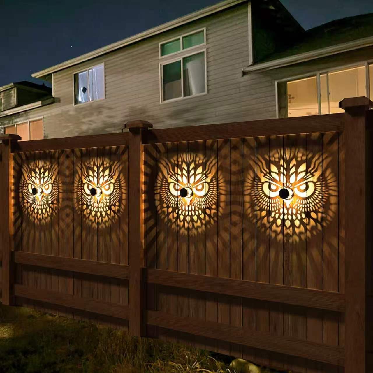Repeated Owl solar shadow lights on a residential wooden fence